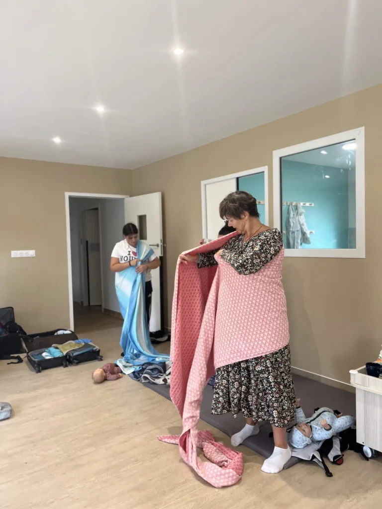 Des professionnels de la petite enfance en crèche apprenant les techniques de portage bébé lors d'une formation spécialisée, afin d'intégrer le portage dans leur pratique quotidienne.