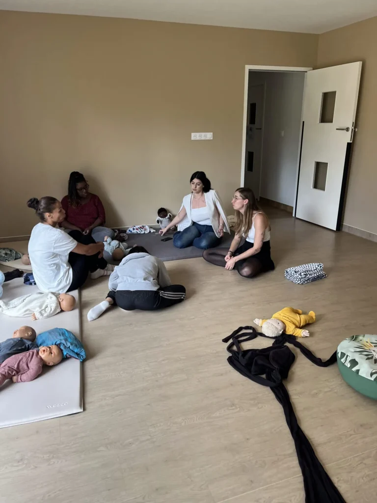 Des professionnels de la petite enfance en crèche apprenant les techniques de portage bébé lors d'une formation spécialisée, afin d'intégrer le portage dans leur pratique quotidienne.